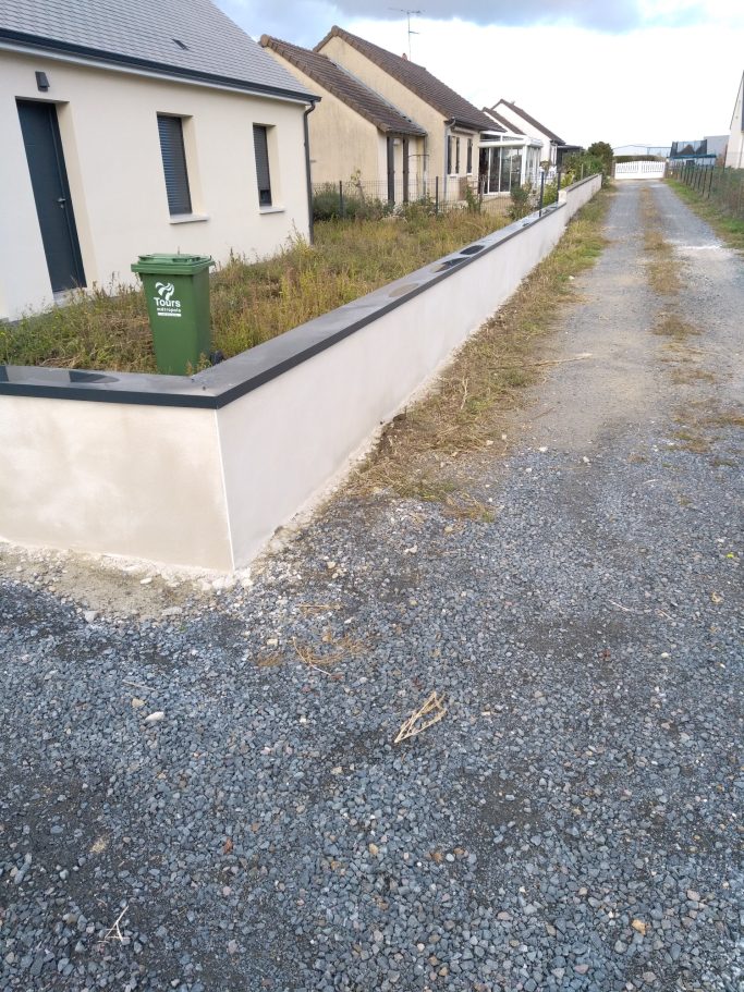 Photo d'un muret de clôture réalisé en parpaing et enduit 